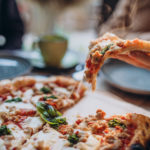 Three firends together eating pizza in a cafe